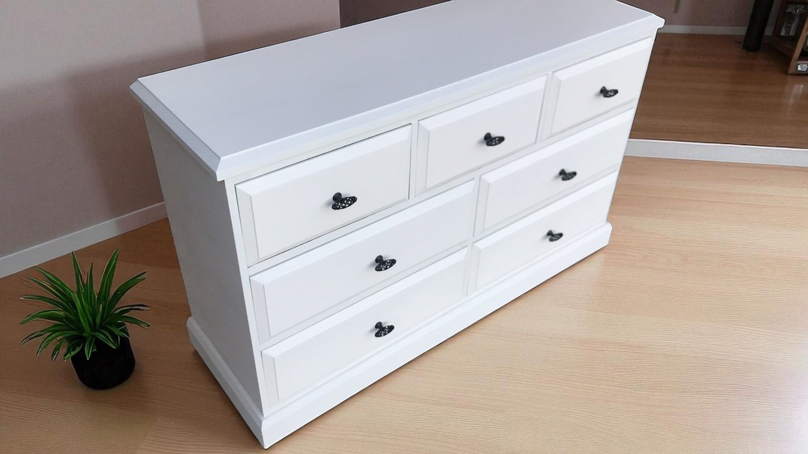 a white dresser with black handles