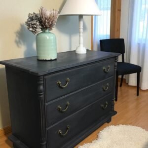 a dresser with a lamp and a vase on top
